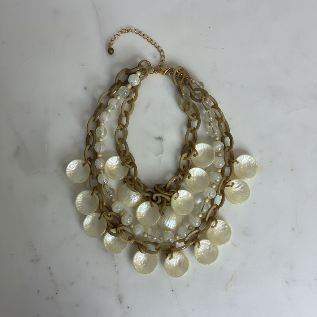 Colar dourado com pérolas sobre mármore