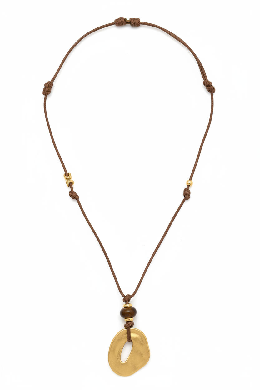 White background gold open oval cord necklace flat lay